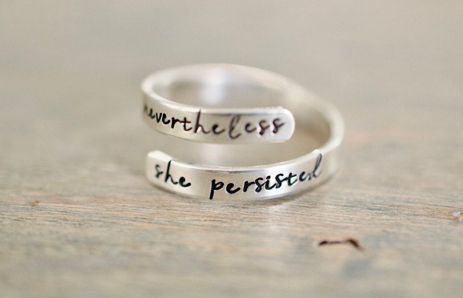 Sterling silver wrap ring with the text "nevertheless" on the top and "she persisted" on the bottom