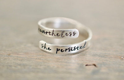 Sterling silver wrap ring with the text &quot;nevertheless&quot; on the top and &quot;she persisted&quot; on the bottom